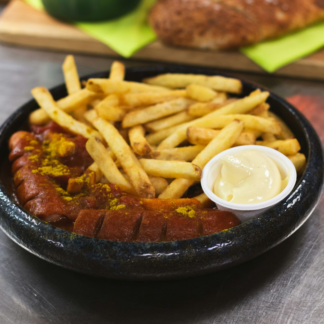 Currywurst with french fries and mayonnaise in a bowl.