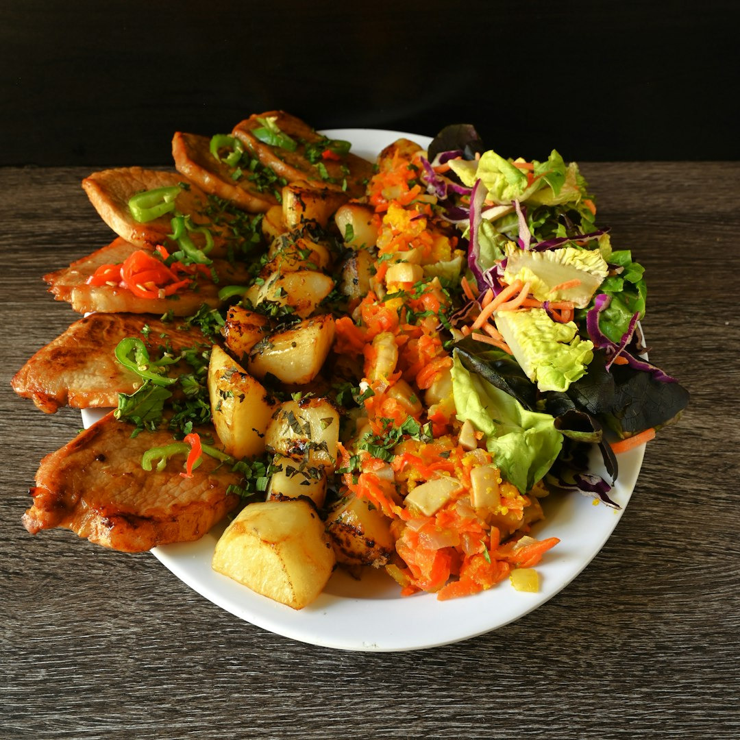 Grilled meat with roasted potatoes and salad on a plate.