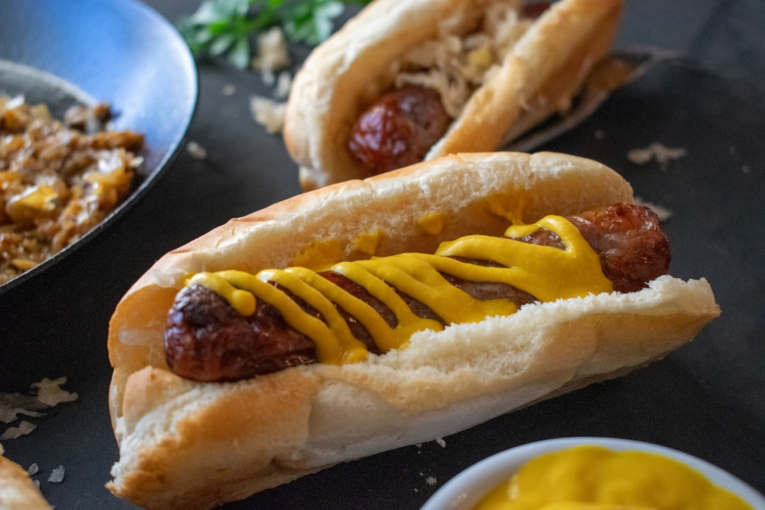Two grilled sausages with mustard in buns.